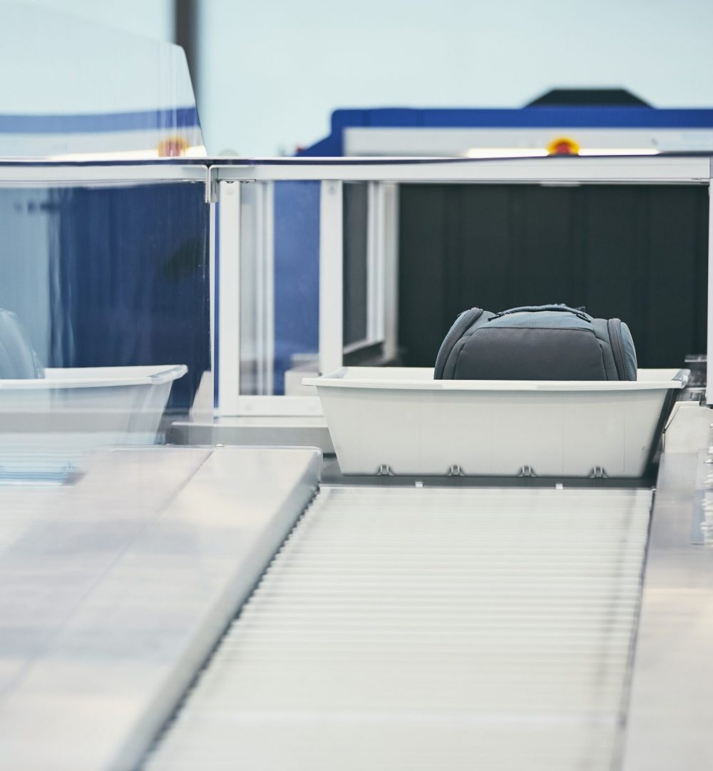 Airport security check. Containers with luggage on conveyor belt after x-ray control.